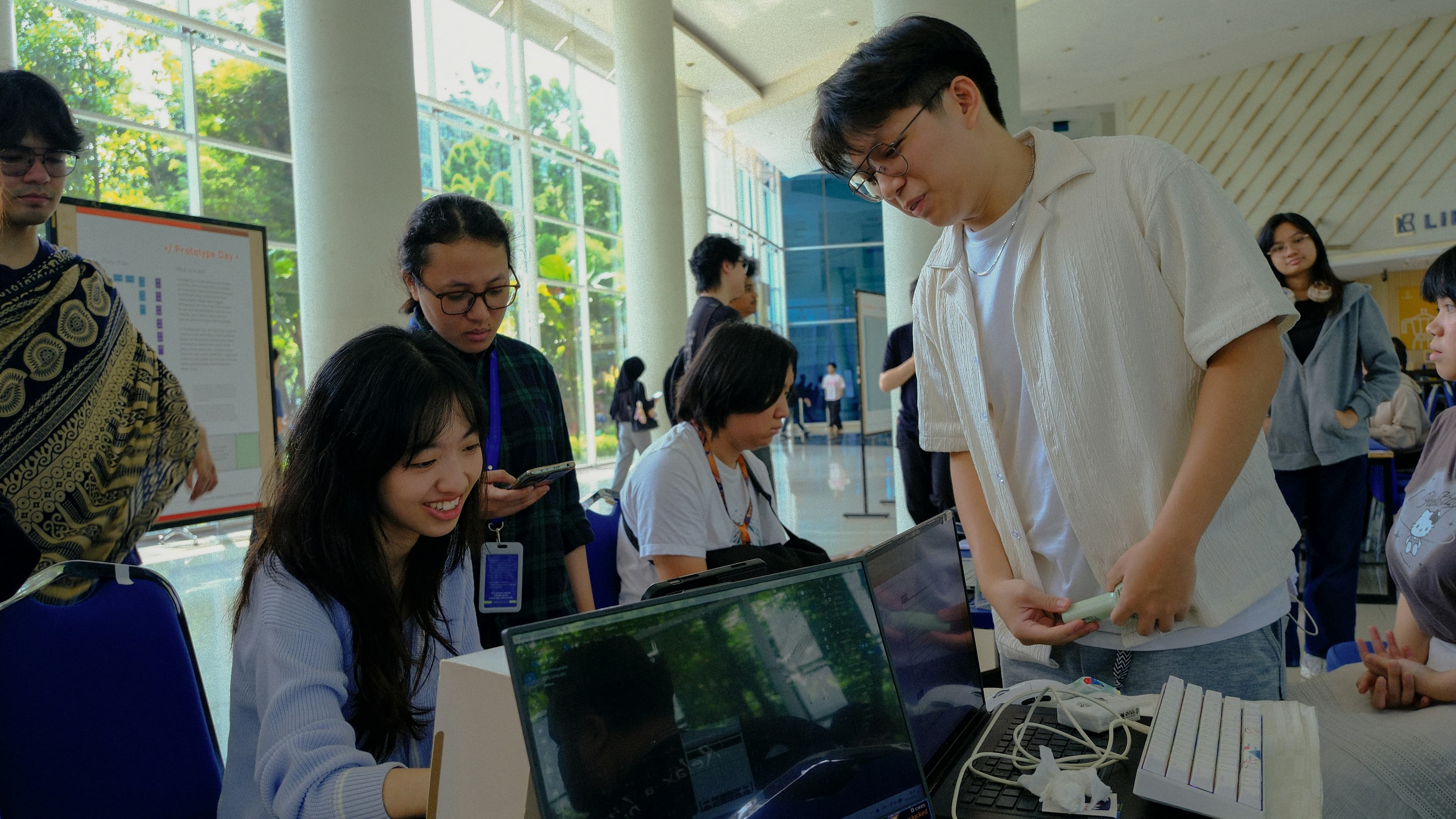 Students gathered around a laptop on prototype day